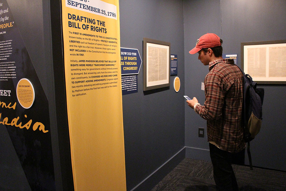 A student reading a document on display in the American Treasures exhibit