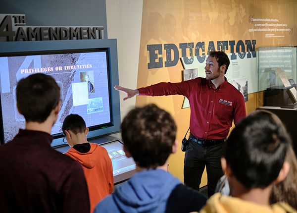 group of younger individuals listening to a presentation in a musuem